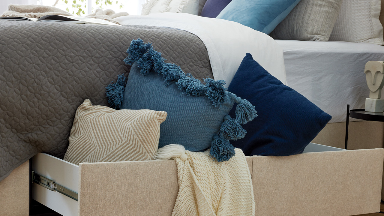 SlumberCorp deepline 4 drawer base, decorated with blue and cream cushions and throw.